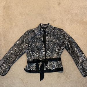 Black, white, and grey waist length jacket with buttons and a tie belt.